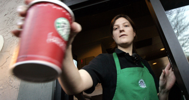A Starbucks barista passes a coffee drink out the window to a customer. On Sunday, Costco, Starbucks, and Whole Foods released a list of six principles for union elections. (AP/Elaine Thompson)