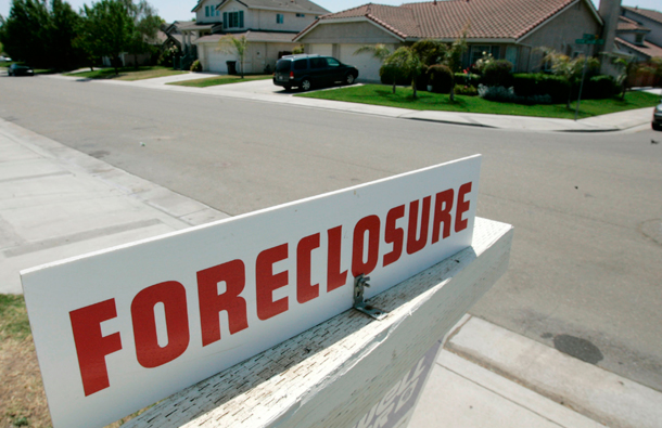 A foreclosure sign is seen on the lawn of a home for sale in Stockton, CA.