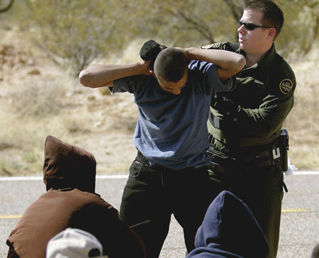 A U.S. Border Patrol Agent searches a man  in Pima County near Three Points, Arizona. (AP/Khampha Bouaphanh)
