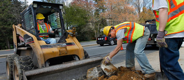 Three American Infrastructure construction workers replace a sidewalk ramp as part of a federal contract in Silver Spring, Maryland. (AP/Jacquelyn Martin)