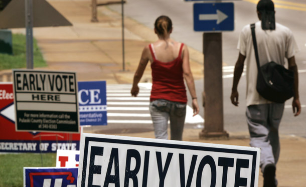 A man and woman walk past political signs near an early voting polling place in Little Rock, Arkansas, this past summer. (AP/Danny Johnston)