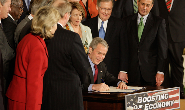 President George W. Bush, surrounded by members of Congress, signs the  Economic Stimulus Act of 2008, Wednesday, February 13, 2008, in the East  Room of the White House in Washington. (AP/Ron Edmonds)