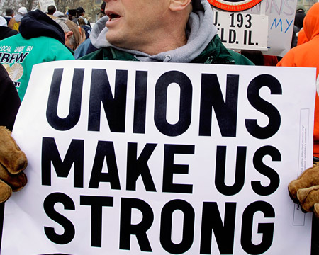 A man holds a sign at the Illinois State Capitol in Springfield. Middle-class incomes have declined as union membership dropped over the last few decades. (AP/Seth Perlman)