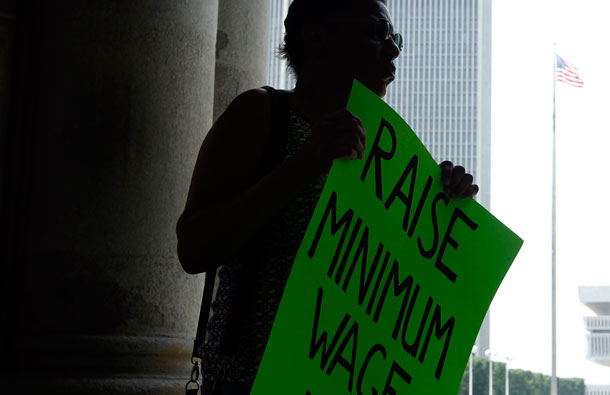 Wendy Brown of Schenectady, New York, holds a sign before an Occupy Albany rally pushing for a raise in the state's minimum wage. Women, especially women of color, would benefit from a boost in the federal minimum wage.<br /> (AP/Mike Groll)