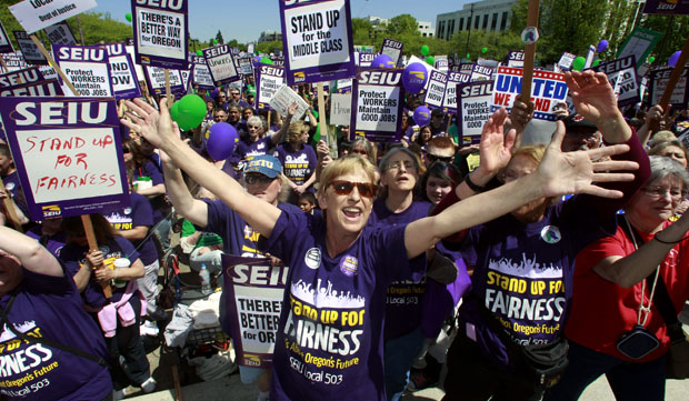 In this May 20, 2011, file photo taken in Salem, Oregon, Cathy Williams, center, of Portland, stands with thousands of state workers gathered at the Oregon Capitol. Oregon is one of the top states in the country when it comes to union membership, with more people joining unions there each year. (AP/Rick Bowmer)