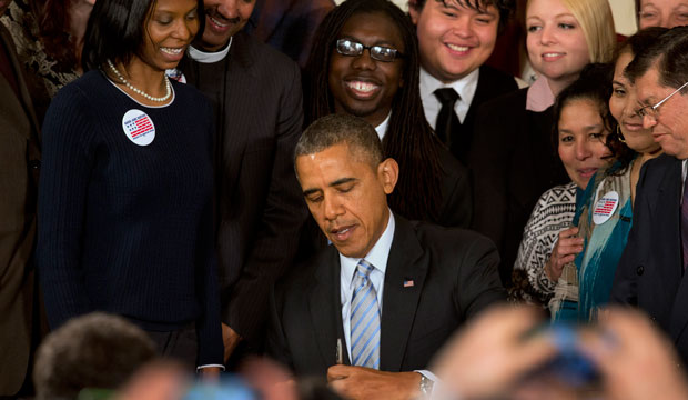 Surrounded by workers, President Barack Obama signs an executive order to raise the minimum wage for federal contract workers to $10.10 per hour during a ceremony at the White House in Washington, February 12, 2014. (AP/Jacquelyn Martin)