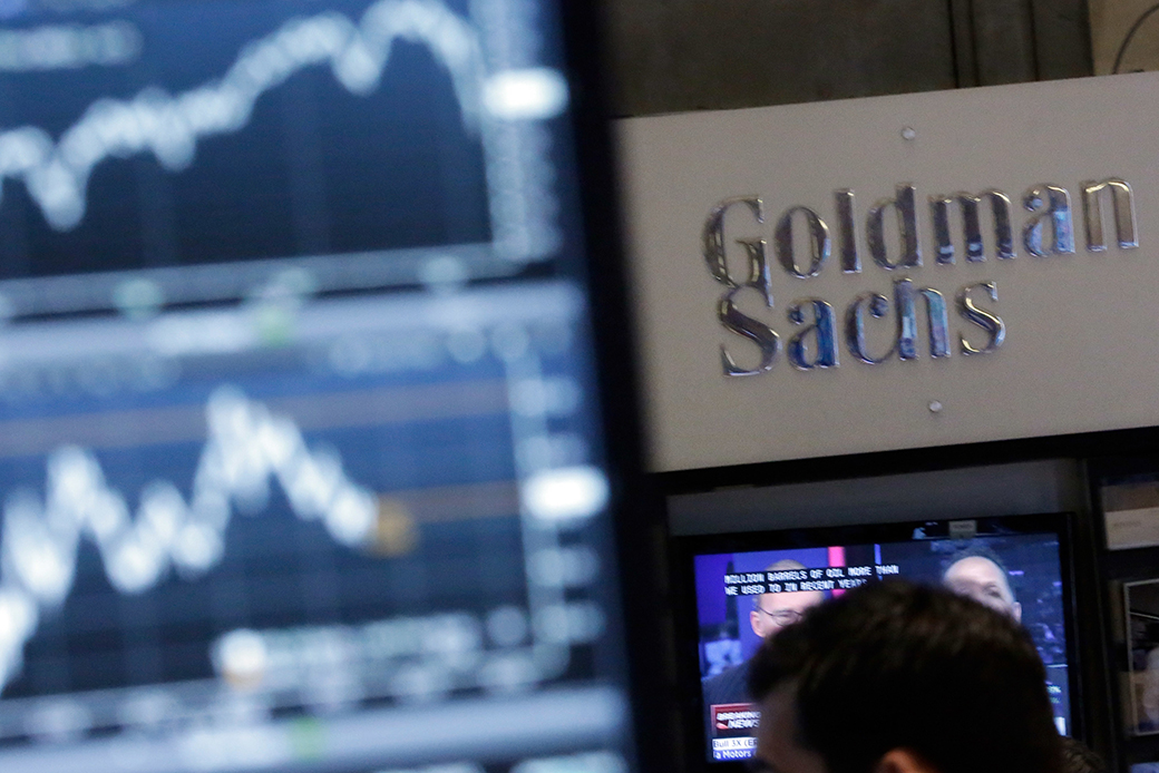 A screen at a trading post on the floor of the New York Stock Exchange is juxtaposed with the Goldman Sachs booth, October 2014. (AP/Richard Drew)
