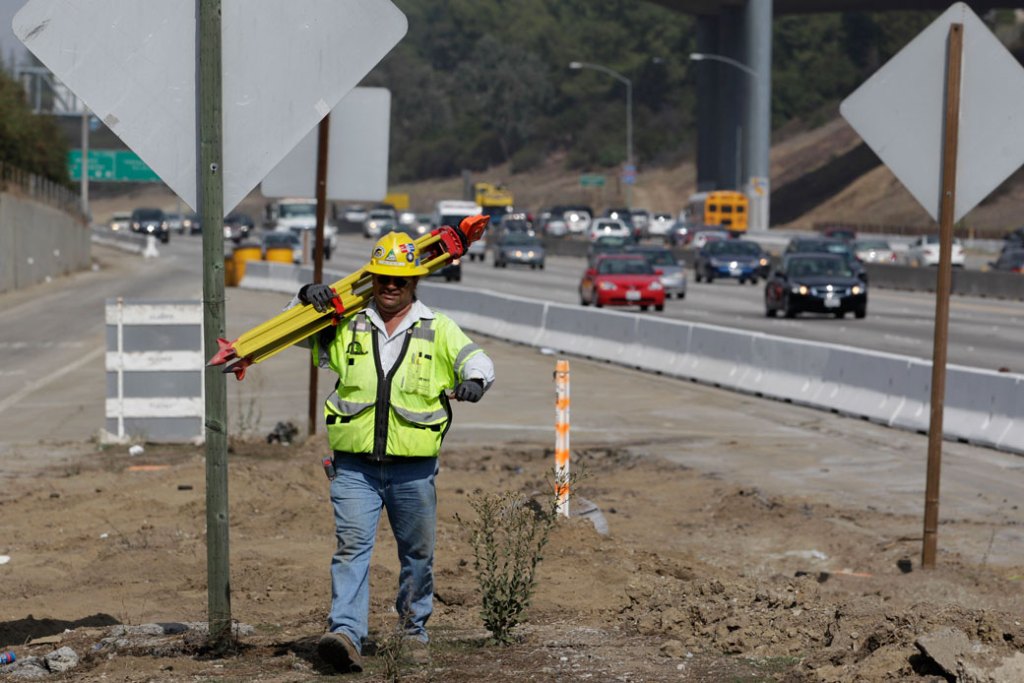 A construction worker carries survey equipment along the 405 Freeway near the Brentwood section of Los Angeles, October 2010. (AP/Jae C. Hong)