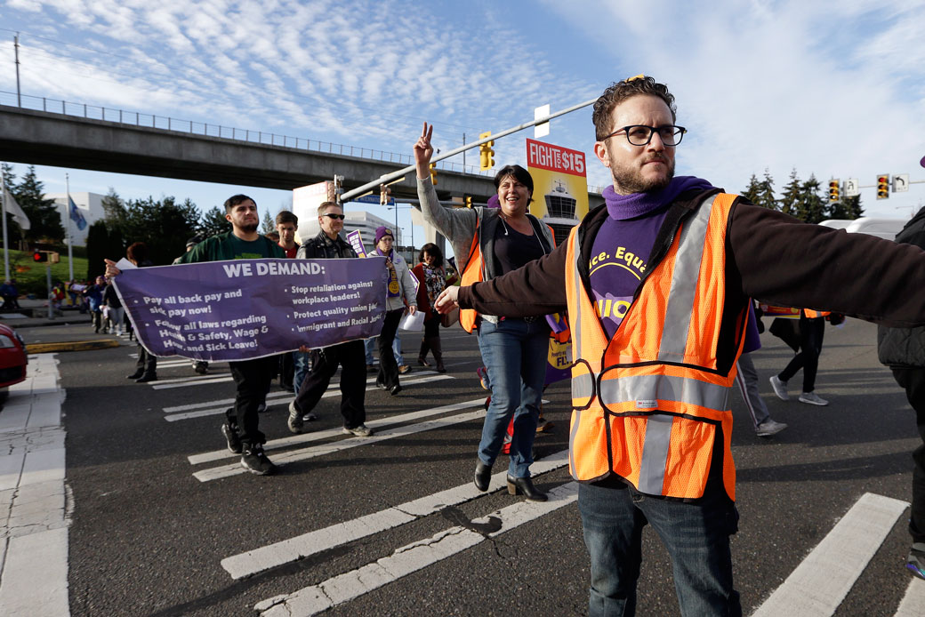 A labor union staffer holds back traffic during a march by demonstrators near Seattle-Tacoma International Airport, November 2016.