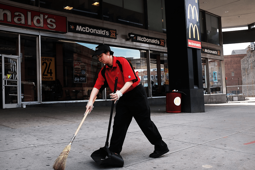  (A McDonald's employee is shown sweeping the sidewalk in front of a store in Brooklyn, New York.)