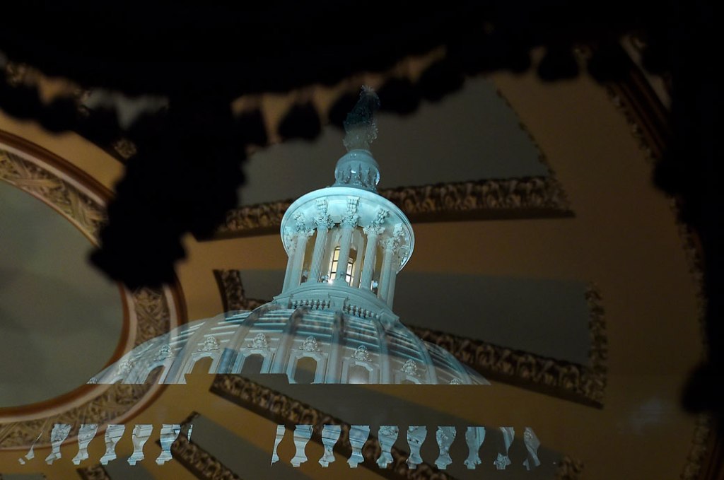 The dome of the U.S. Capitol is seen reflected in a window of the Ohio Clock corridor outside the chamber where cenators debate during the impeachment trial of President Donald Trump, January 2020. (Getty/Olivier Douliery)