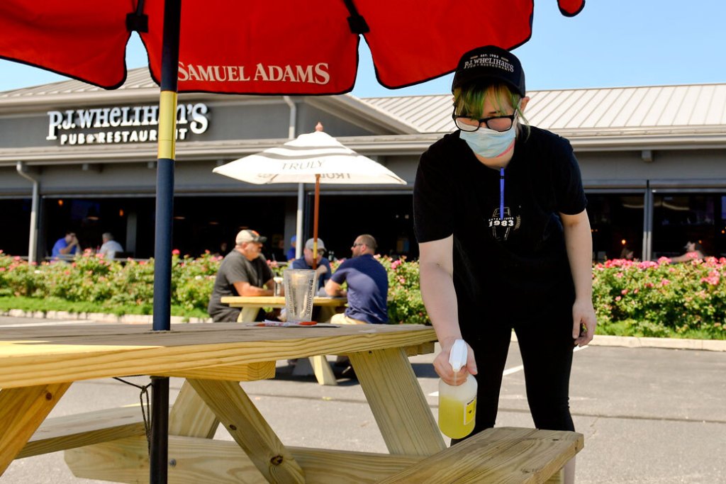 A server disinfects an outdoor table, June 2020. (Getty/Ben Hasty)