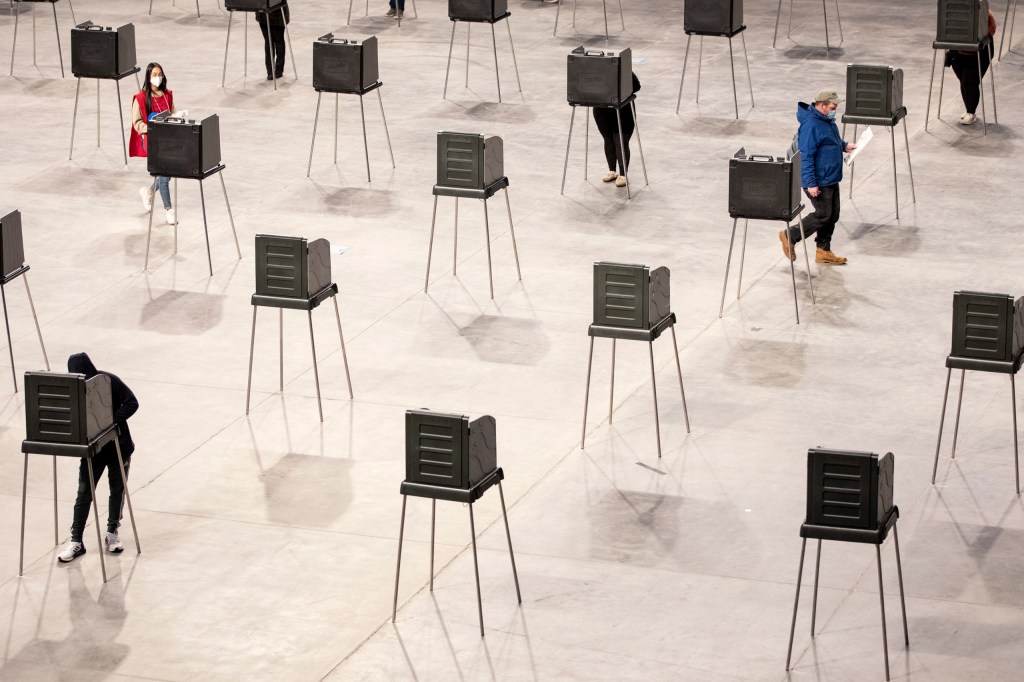 BANGOR, ME - NOVEMBER 3: A poll worker walks over to sanitize a voting booth after a voter leaves to walk their ballot over to the machines at Cross Insurance Center on Tuesday, November 3, 2020. (Staff photo by Brianna Soukup/Portland Press Herald via Getty Images)