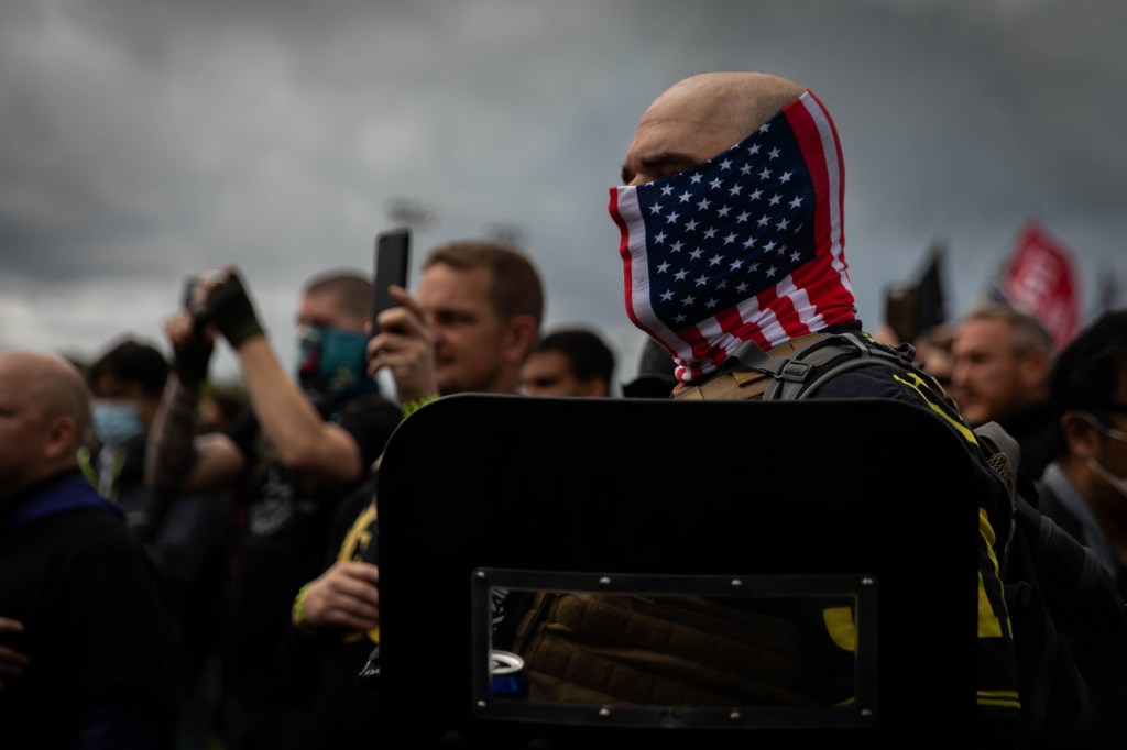 A man hold his hand to his heart as a Proud Boys organizer recites the Pledge of Allegiance during a Proud Boys rally at Delta Park in Portland, Oregon on September 26, 2020. - Far-right group 