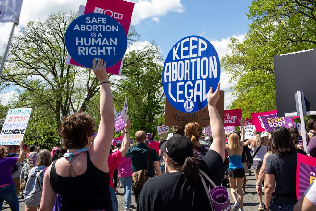 Photo shows a crowd of people holding signs that read 