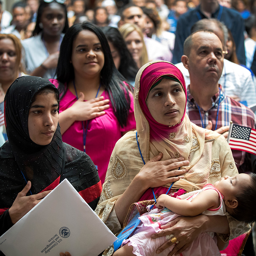 A woman, originally from Bangladesh, holds her 7-month-old daughter as she recites the Pledge of Allegiance.