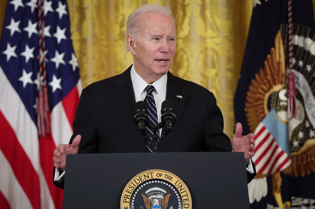 Photo shows Joe Biden speaking behind a podium with the American flag behind him.