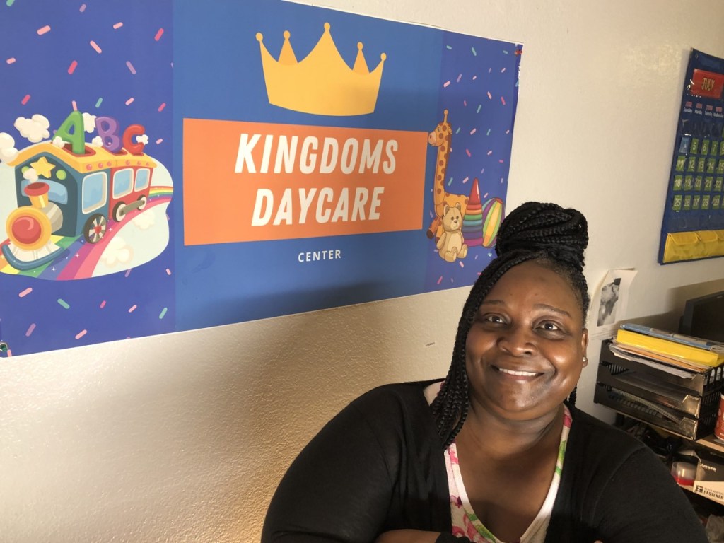 Anitra Lott sits next to her child care center sign in June 2022.