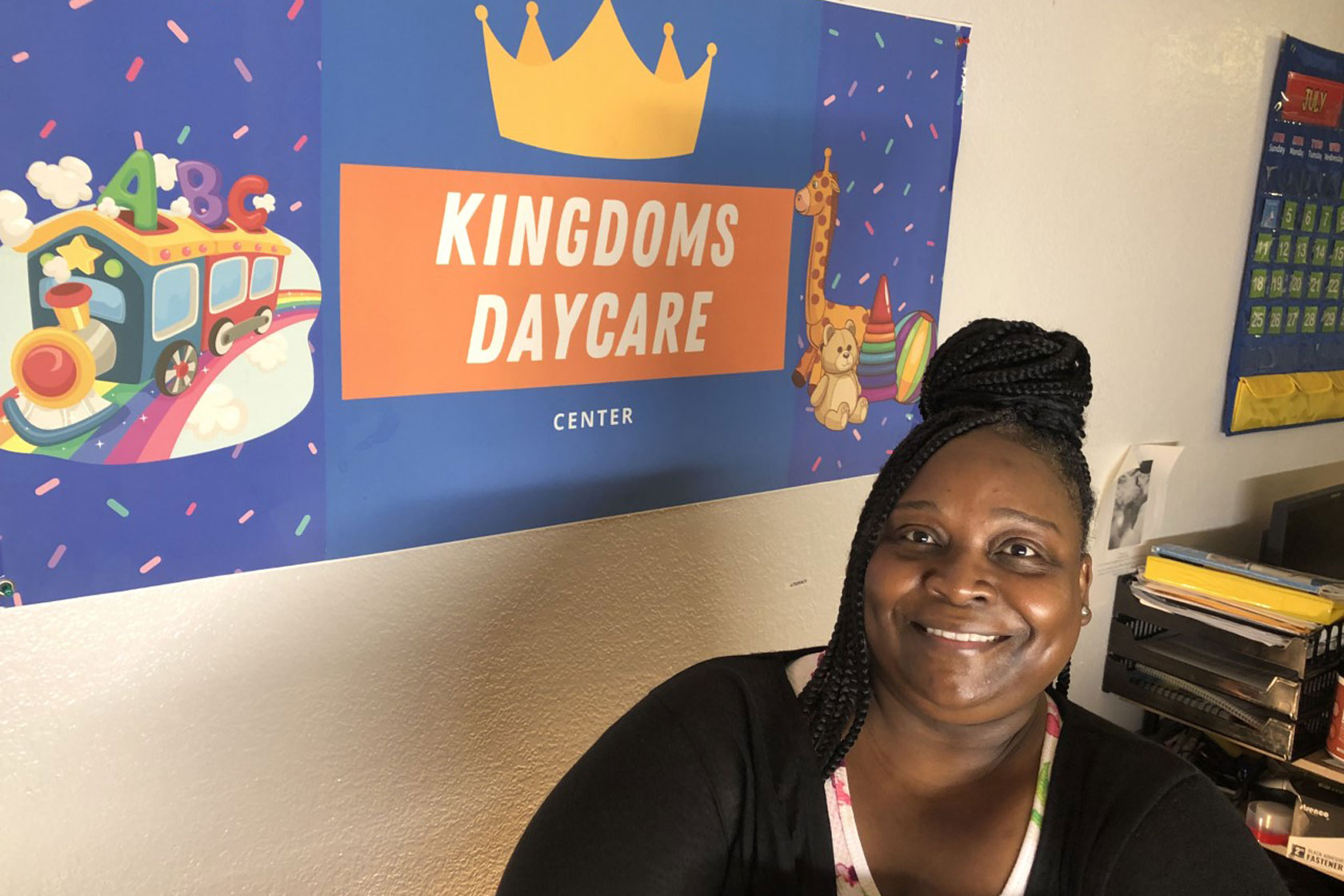 Anitra Lott sits next to her child care center sign in June 2022. (Photo credit: Anitra Lott) 