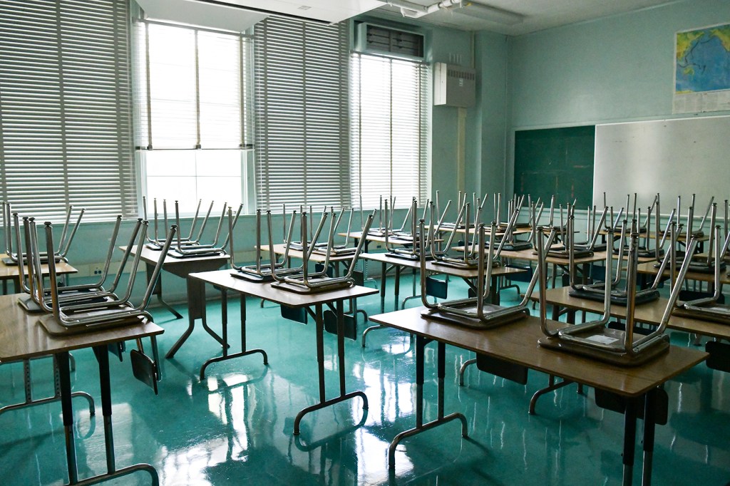 Empty classroom with chairs on top of desks