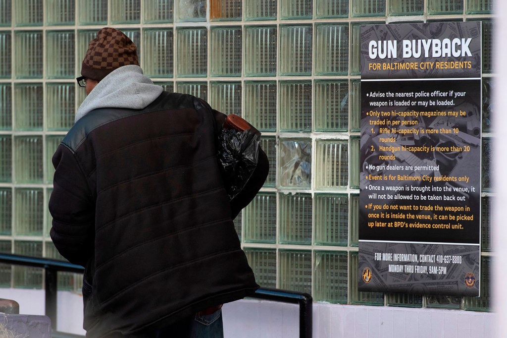 Man walking by a gun buyback poster