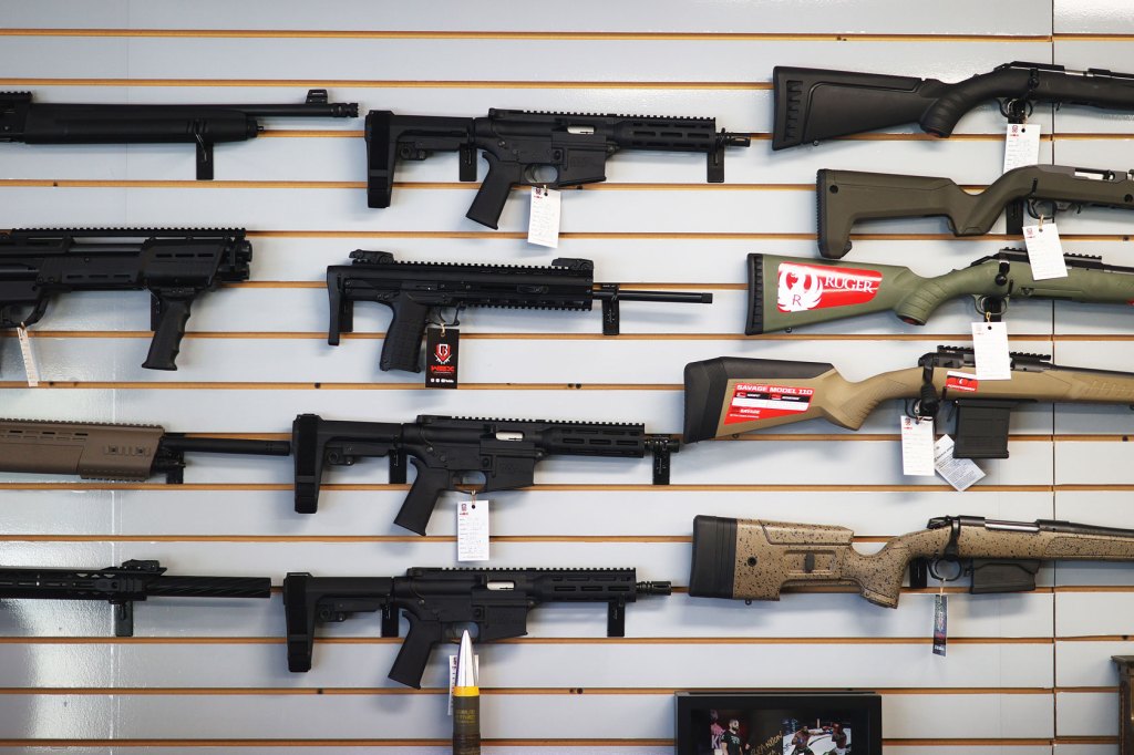 Several guns hang on a wall at a store.