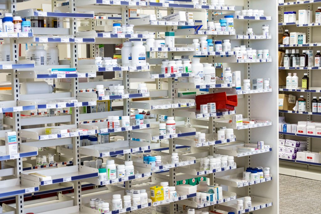 Shelves in a pharmacy filled with bottles prescription pills.