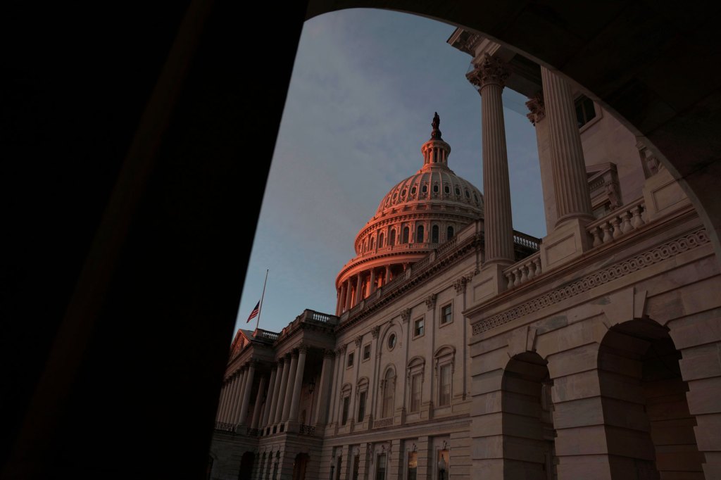 Photo shows the U.S. Capitol building dome glowing pink during a sunrise