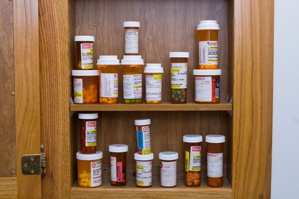 An open medicine cabinet filled with prescription pills.