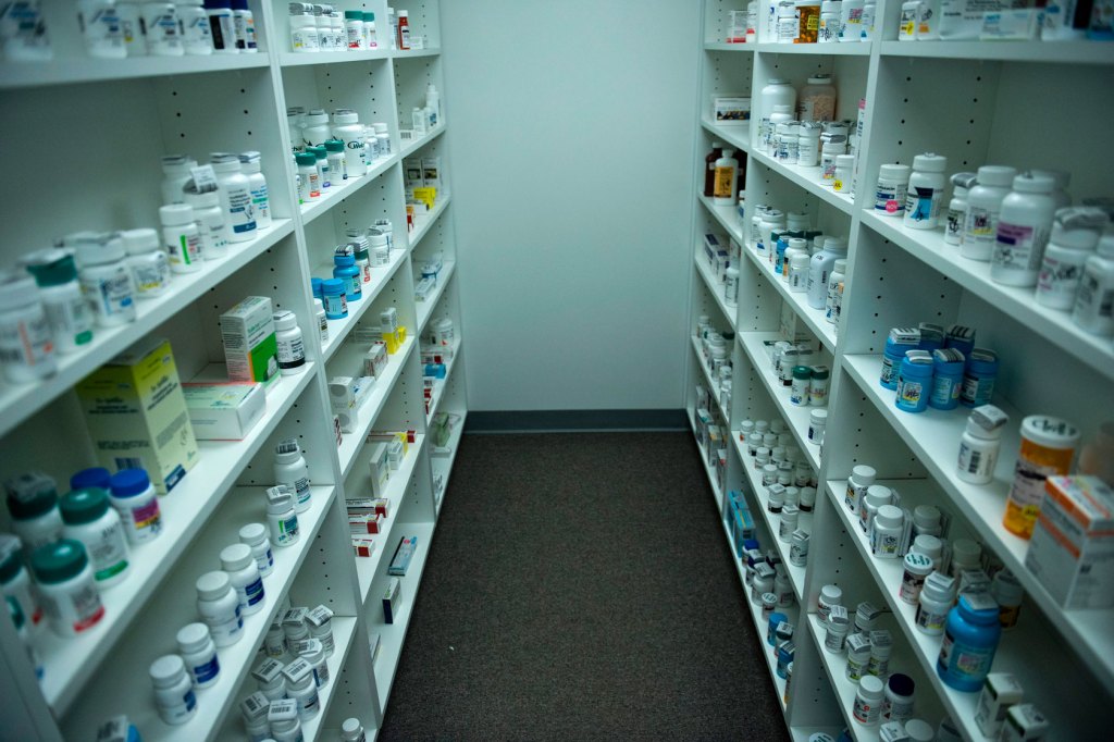 Two shelves are lined with prescription pill bottles.