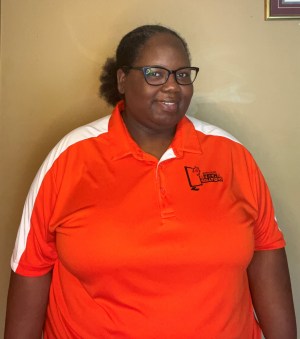 Photo shows Regina Monds smiling at the camera wearing an orange shirt.