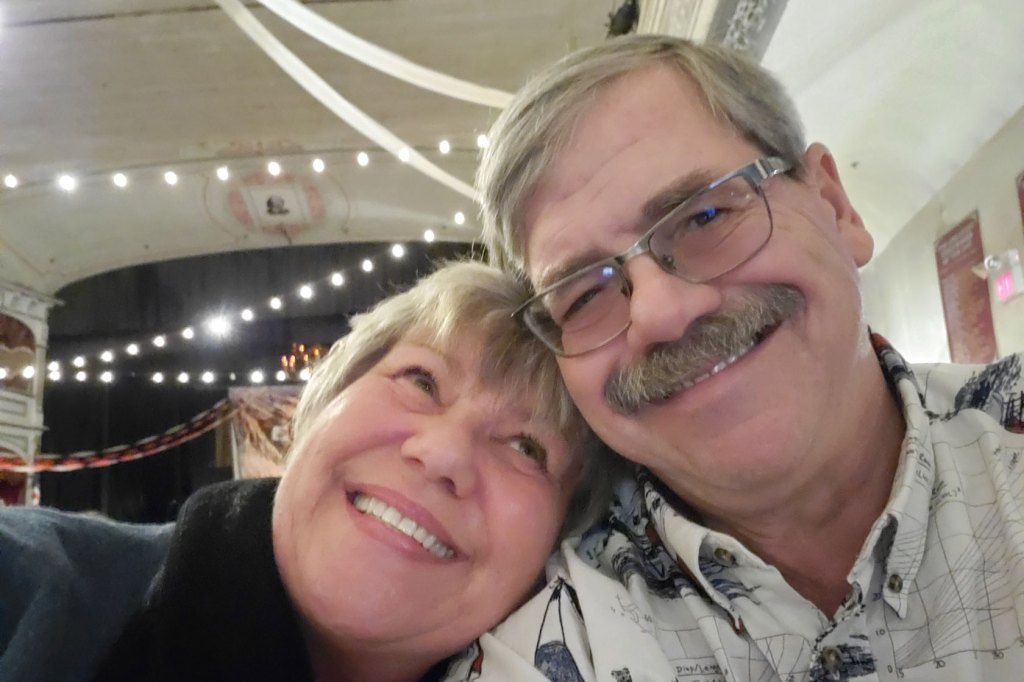 Steve Zulke and his wife, who leans on his shoulder and looks up at him, smile for the camera.
