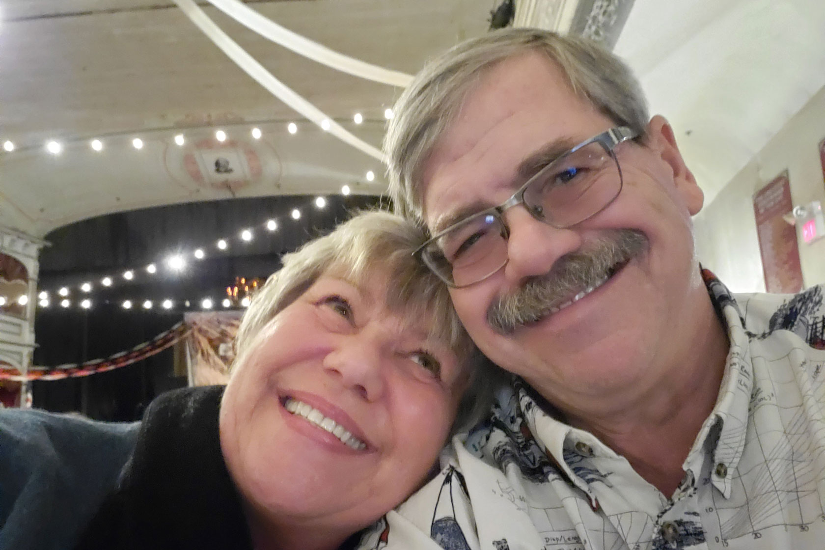 Steve Zulke and his wife, who leans on his shoulder and looks up at him, smile for the camera.