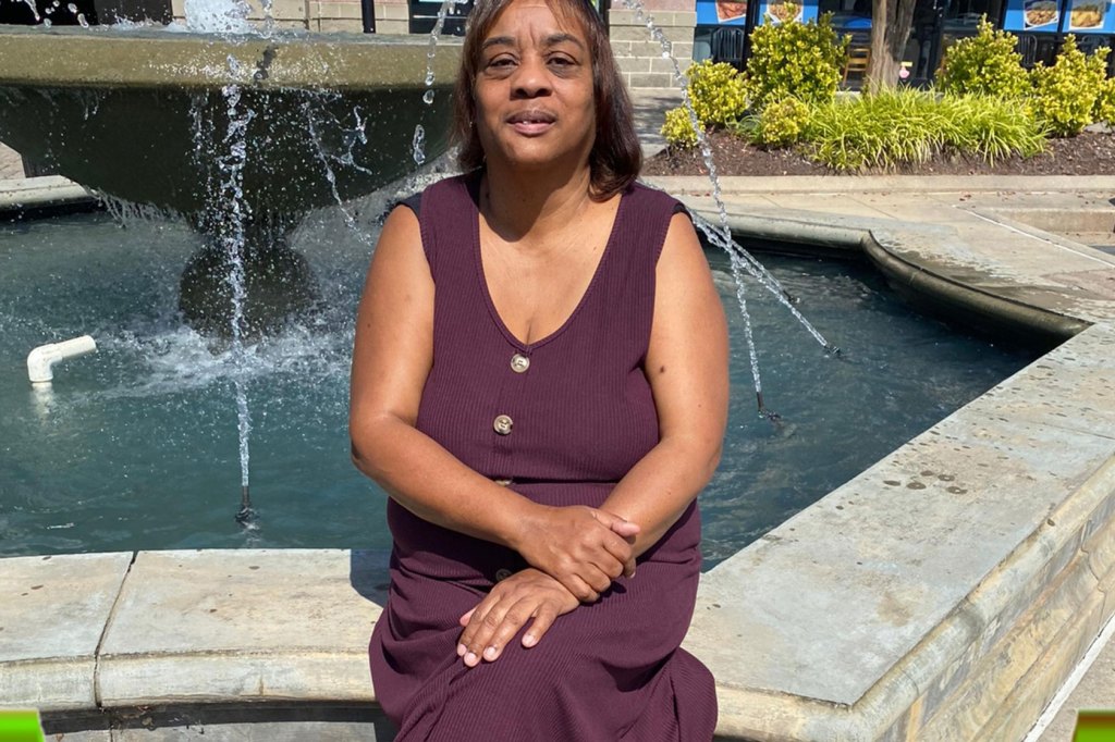 Photo shows Bernetha Patterson sitting in front of a fountain wearing a purple dress