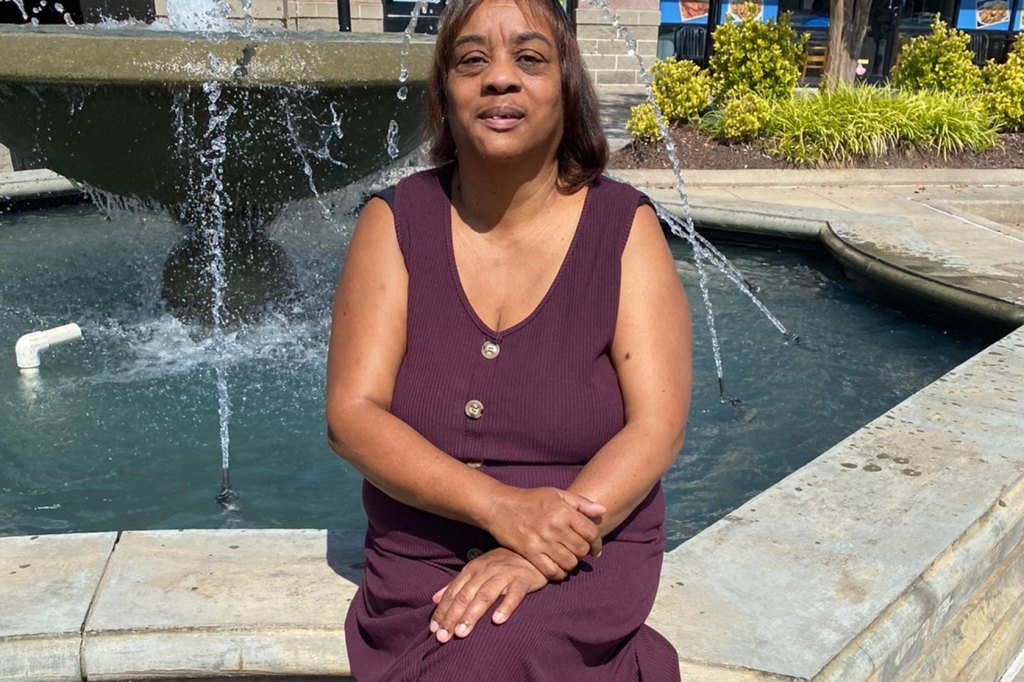 Photo shows Bernetha Patterson sitting in front of a fountain wearing a purple dress