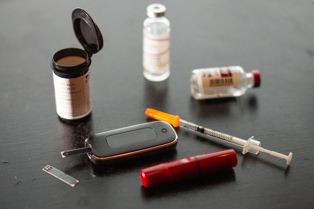 A needle and insulin are seen on a table.