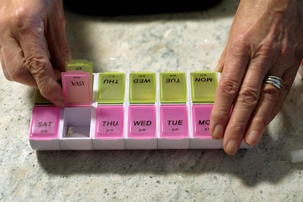 A woman opens a pill box.