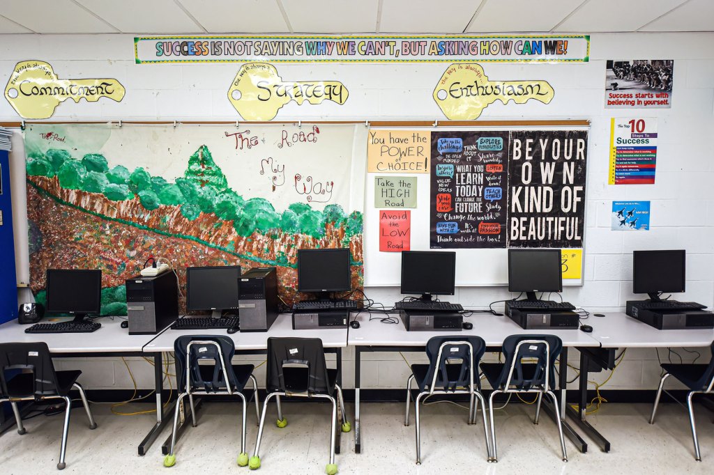 Computer stations are seen in front of colorful student art and sign that says, 
