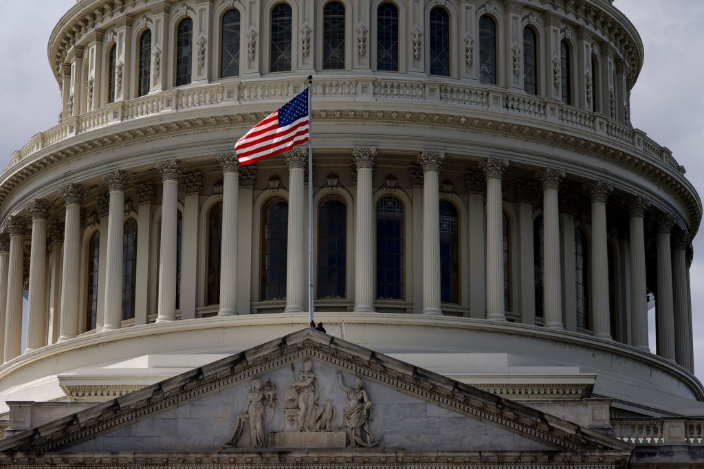 The Capitol is seen up close with the American flag waving before it.