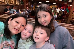 Photo shows Kandie Guynn posing with her three young children at a restaurant