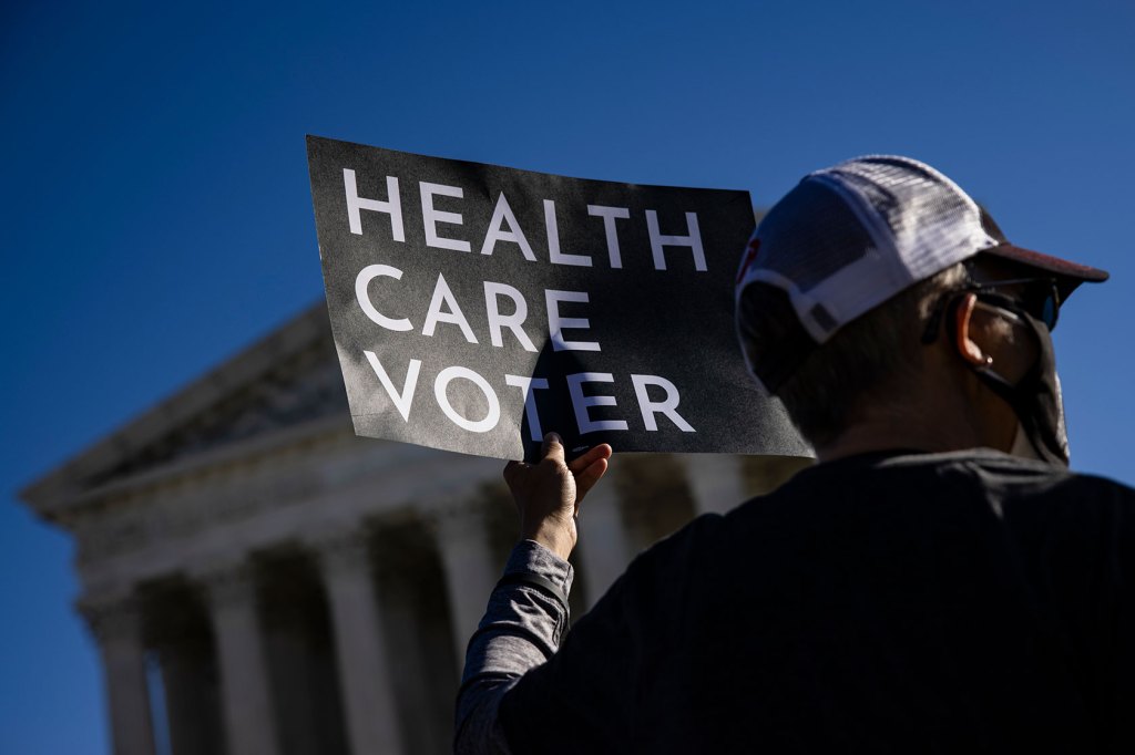 A supporter of the Affordable Care Act (ACA) stands in front of the U.S. Supreme Court.