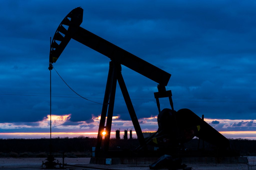 The sun sets behind oil wells in Texas.
