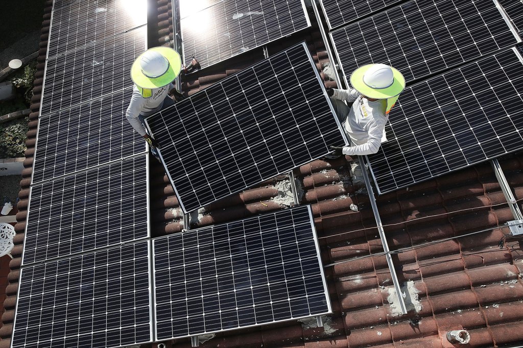 Workers install a solar panel system on the roof of a home in Palmetto Bay, Florida.