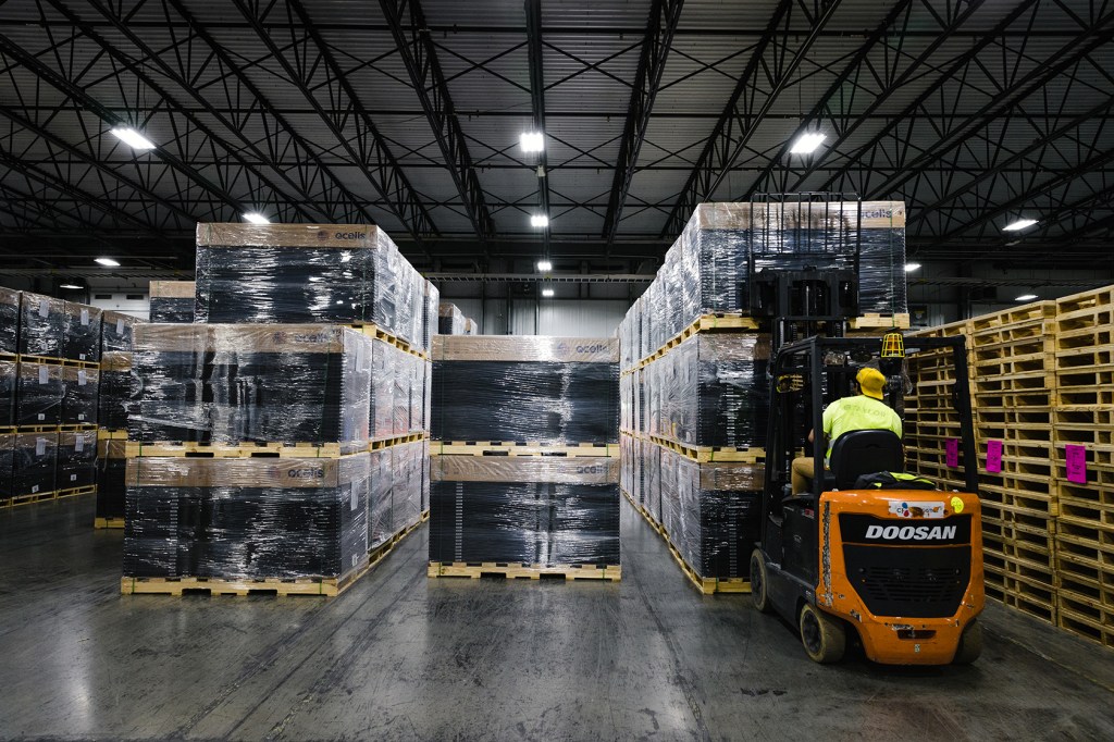 Worker moving solar panels on assembly floor