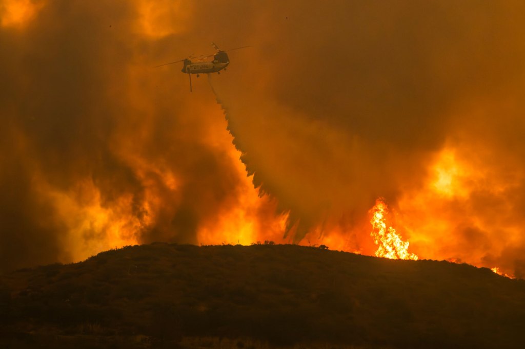 A Cal Fire helicopter makes a water drop.
