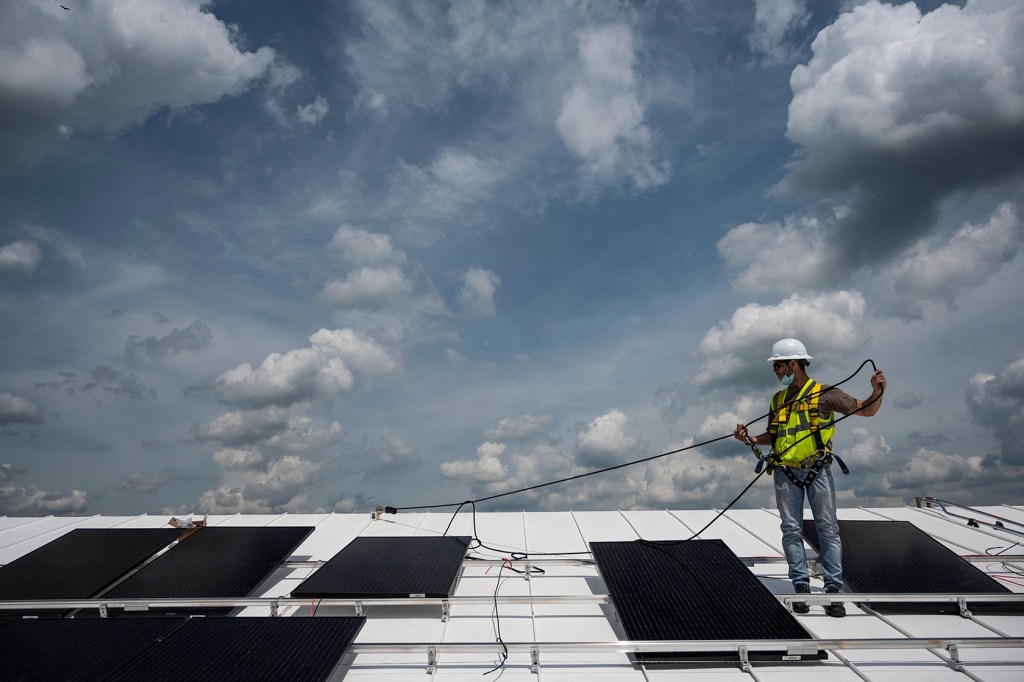 An worker installs solar panels on the roof of a church.
